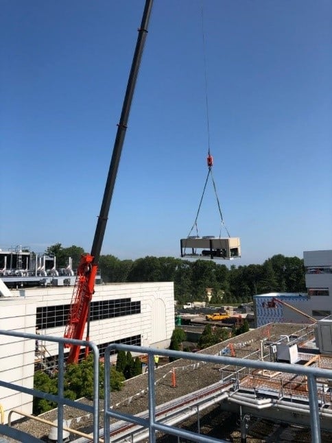 Crane used to install condenser units on roof for refrigeration system.