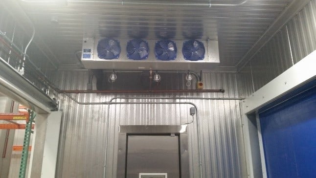 Four evaporator units in cooler vestibule for medical freezer storage.