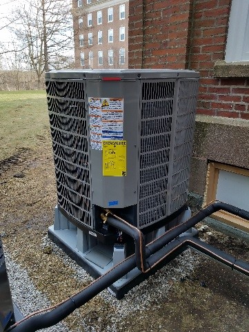 Outdoor central air conditioning unit with heat pump in Weston, MA.