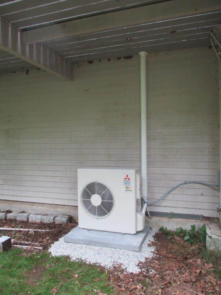 Condenser for ductless air conditioning located under the deck of a Beverly, MA home