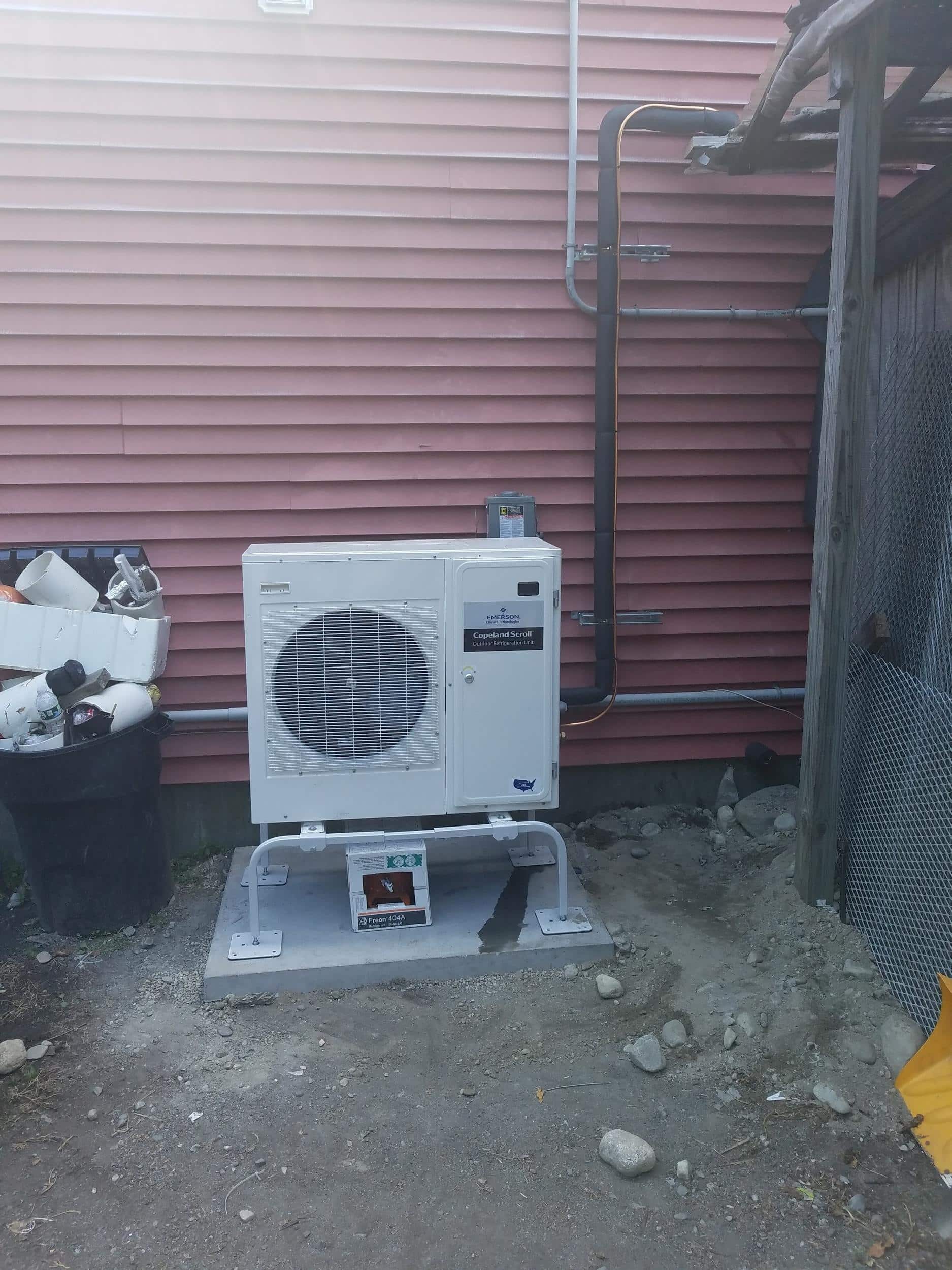 Properly installed condenser unit for a refrigeration system placed on a poured concrete pad.