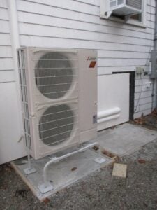 Outdoor condenser unit installed on a concrete pad outside Beverly, MA, home.