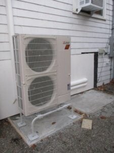 Outdoor condenser unit installed on a concrete pad outside Beverly, MA, home. 