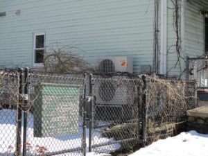 A Mitsubishi Electric ductless heat pump outdoor condenser unit installed outside Victorian home. 