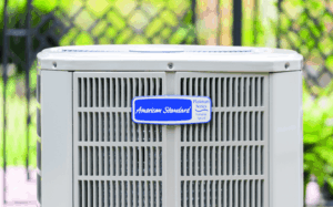 A close-up view of an American Standard Platinum Series outdoor air conditioning unit with a metal grille and blue label.