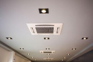 A ceiling with recessed spotlights and multiple rectangular ceiling-mounted air conditioning vents.