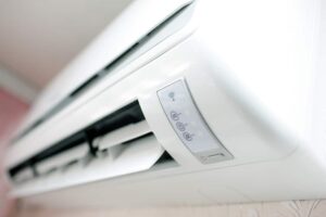 Close-up view of a white wall-mounted air conditioner unit with visible control panel and indicator lights.