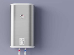 A wall-mounted stainless steel water heater with a temperature gauge and two colored inlet and outlet pipes against a plain light purple background.